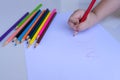 The child`s hand preparing to write on a white sheet of paper with colored pencils.  Education and children activities concept Royalty Free Stock Photo