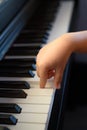 A kid hand presses the piano keys. Early musical development in young children