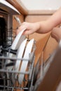 Child's hand put plate in dishwasher. Royalty Free Stock Photo