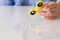 Child`s hand spinning a fidget spinner device. Playing with a yellow hand spinner fidget toy