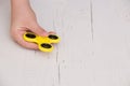 Child`s hand spinning a fidget spinner device. Top view. Playing with a yellow hand spinner fidget toy