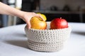 Child`s hand taking a beautiful red apple from a knitted basket. Home interior, diet food. Health concept