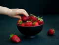 Child`s hand taking a strawberry from a bowl Royalty Free Stock Photo