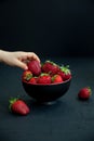 Child`s hand taking a strawberry from a bowl Royalty Free Stock Photo