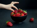 Child`s hand taking a strawberry from a bowl Royalty Free Stock Photo