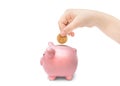 The child`s hand throws the coin into a piggy bank on white background