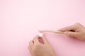 Child`s hand with toothbrush and white platic tooth on pink background