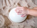 Child's hand touching egg on the sand Royalty Free Stock Photo
