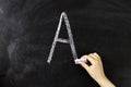 child's hand writes the letter A on the board Royalty Free Stock Photo