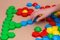 Child`s hands add colored mosaic details to the drawing on the table. Leisure of the child in confinement. Table game