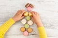 Child`s hands arranging macarons.