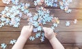 The child`s hands collect folded puzzles against the background of a wooden table