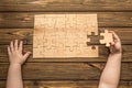 The child`s hands collect a puzzle on the background of a wooden table. Royalty Free Stock Photo