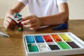 The child`s hands are engaged in modeling from plasticine on a table on which there is a box of plasticine, close-up, side view Royalty Free Stock Photo