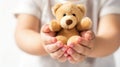 Child\'s hands gently holding a small teddy bear, symbolizing innocence and care