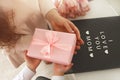 Child`s hands hold beautiful pink gift box with ribbon. Pink tulip flower and sign i love you mom in background. Top view, close- Royalty Free Stock Photo