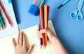 A child`s hands hold colored pencils on the background of school supplies-the concept of preparing a child for school classes Royalty Free Stock Photo