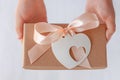 Child`s hands hold gift box with ribbon bow and heart card tag. Brown kraft paper packaging flat lay. Donation concept Royalty Free Stock Photo