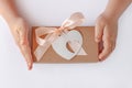Child`s hands hold gift box with ribbon bow and heart card tag. Brown kraft paper packaging flat lay. Donation concept Royalty Free Stock Photo