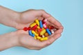 Child`s hands hold many colorful vitamins, capsules, supplements, pills