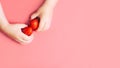 Child`s hands holding strawberries on pink