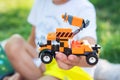 A child s hands holding a toy truck made of building blocks. The truck is orange and black with stripes on the side. The Royalty Free Stock Photo