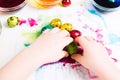 Child`s hands moving colorful easter quial eggs on the tissue