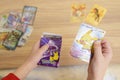 A child\'s hands placing rare collectible Pokemon trading cards on a wooden table