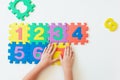 Child`s hands playing with numbers, learning simple multiplication. Colorful bright puzzle numbers on white background, education