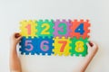 Child`s hands playing with numbers, learning simple multiplication. Colorful bright puzzle numbers on white background, education Royalty Free Stock Photo