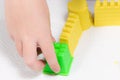 A child`s hands playing with yellow magic sand and building, kne