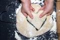 Child`s hands taking a cutted dough heart. Little child preparing dough for backing. A photo from above of Kid`s hands, some flo