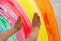 Child`s hands touch painting rainbow on window