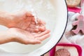 ChildÃ¢â¬â¢s hands under white bowl with water upon water stream Royalty Free Stock Photo