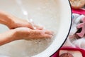 ChildÃ¢â¬â¢s hands under white bowl with water upon water stream Royalty Free Stock Photo