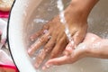 ChildÃ¢â¬â¢s hands under white bowl with water upon water stream Royalty Free Stock Photo