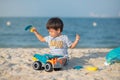 Child\'s Joyful Beach Adventure. Baby boy playing on the beach with a toy truck Royalty Free Stock Photo