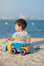 Child\'s Joyful Beach Adventure. Baby boy playing on the beach with a toy truck Royalty Free Stock Photo