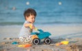 Child\'s Joyful Beach Adventure. Baby boy playing on the beach with a toy truck Royalty Free Stock Photo