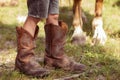 The child`s legs in cowboy boots and the legs of the horse next to each other. Cowboy concept. Royalty Free Stock Photo