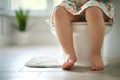 Child\'s legs hanging down from a potty in a bathroom. Training a toddler to use a toilet. Potty training, hygiene, childhood