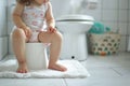 Child\'s legs hanging down from a potty in a bathroom. Training a toddler to use a toilet. Potty training, hygiene, childhood