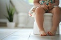 Child\'s legs hanging down from a potty in a bathroom. Training a toddler to use a toilet. Potty training, hygiene, childhood