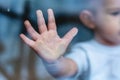 Child`s small hand is pressed against the window glass with reflection. Loneliness of children. Orphanage and orphans