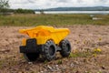 A child`s yellow dump truck abandoned on the ground by a lake, taken at ground level Royalty Free Stock Photo