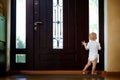 The child is sad and waiting near the front door to be picked up and looks out the window into the street Royalty Free Stock Photo