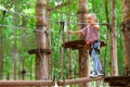 Child in safety harness pass obstacle in adventure rope park Royalty Free Stock Photo