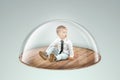 Child safety, overprotection, a little boy sits under a glass dome, cap. Vaccinations, protection against viruses and diseases, Royalty Free Stock Photo