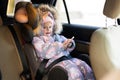 Child safety seat chair baby girl with mobile phone at hands is on back seat of car Royalty Free Stock Photo