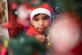 Child in Santa cap decorating Christmas Tree